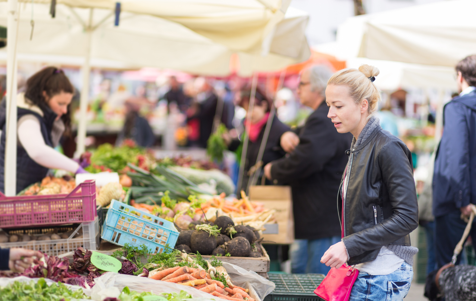 Woman standing at a market stall looking at carrots at St Phillips Sunday market.